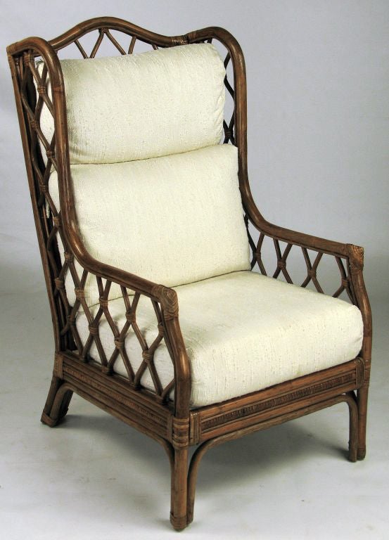 A traditional Chippendale form is interpreted in the non-traditional material of rattan. Treillage inserts in the back and side panels maintain the lighter feel, with the subtle light upholstery accenting the darker frame.