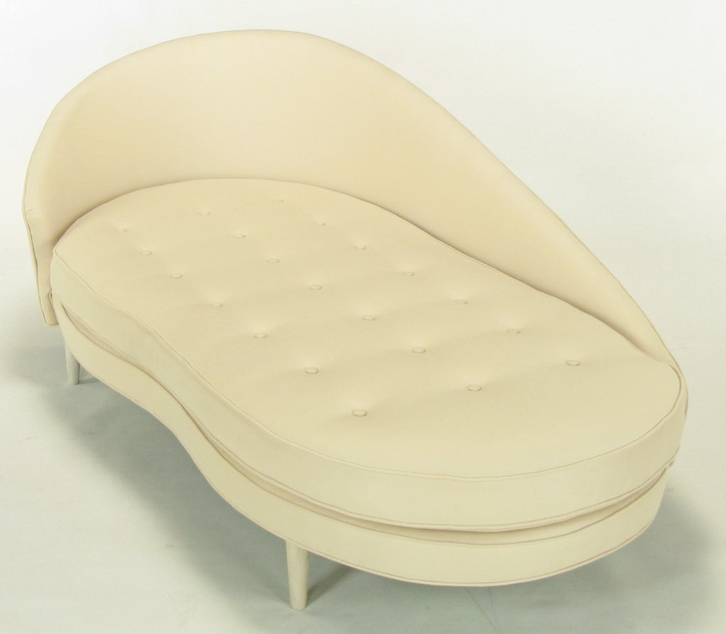 Metropolitan Furniture chaise longue covered in new cream wool upholstery and updated ivory glazed maple legs. Sinuous front side is accentuated by the kidney shaped button tufted cushion and the sloping back that tapers down to the curvature of the