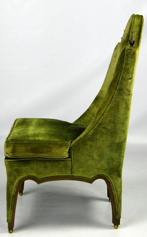 An unusually designed side or slipper chair, with the legs trimmed in walnut wood set atop spherical brass feet. Green velvet upholstery is accented by tall brass finials on top of each side of the chair back.