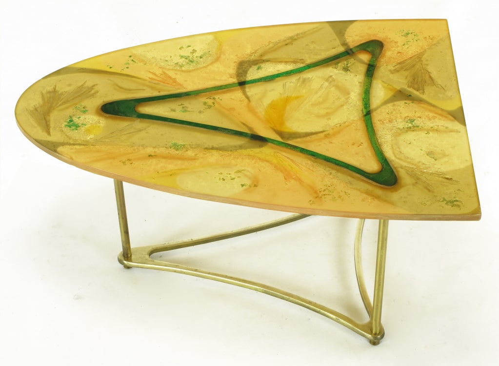 One third surf board shaped side table on triangular brass base. Three brass legs attach the triangular brass base to the abstract designed umber, gold and green semi opaque resin top. One of a kind artist designed coffee table.  Looks to be of