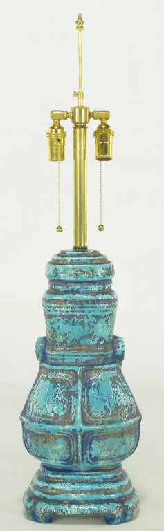 Uncommon ceramic table lamp in the form of an Asian inspired primitive urn. Turquoise and royal blue glazed ceramic body with parcel gilt overlay. Brass stem and double socket cluster. Sold sans shade.