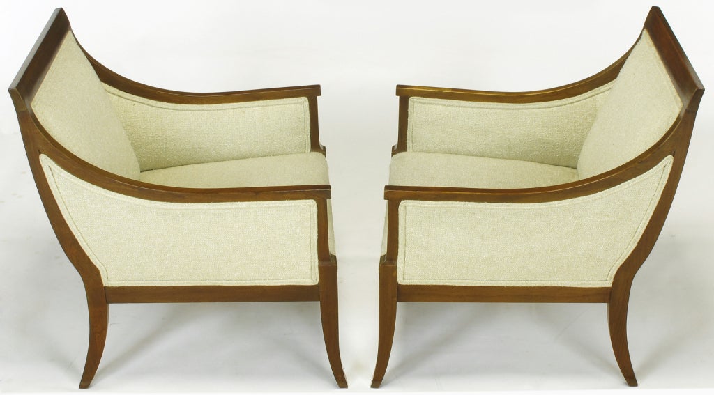 Pair of glazed mahogany wood framed lounge chairs with fixed seat and back cushions. Excellent profile with saber legs and sloped backs, covered in heavy linen upholstery. Excellent build quality on par with that of Baker and Widdicomb.