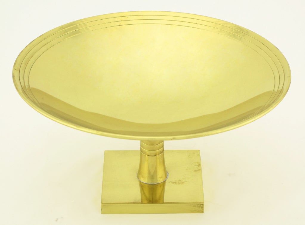 Brass plated brass footed compote by Tommi Parzinger for Dorlyn-Silversmiths. Square pedestal base with a three ring incised stem and shallow bowl with three incised rings and a delicate turned lip.