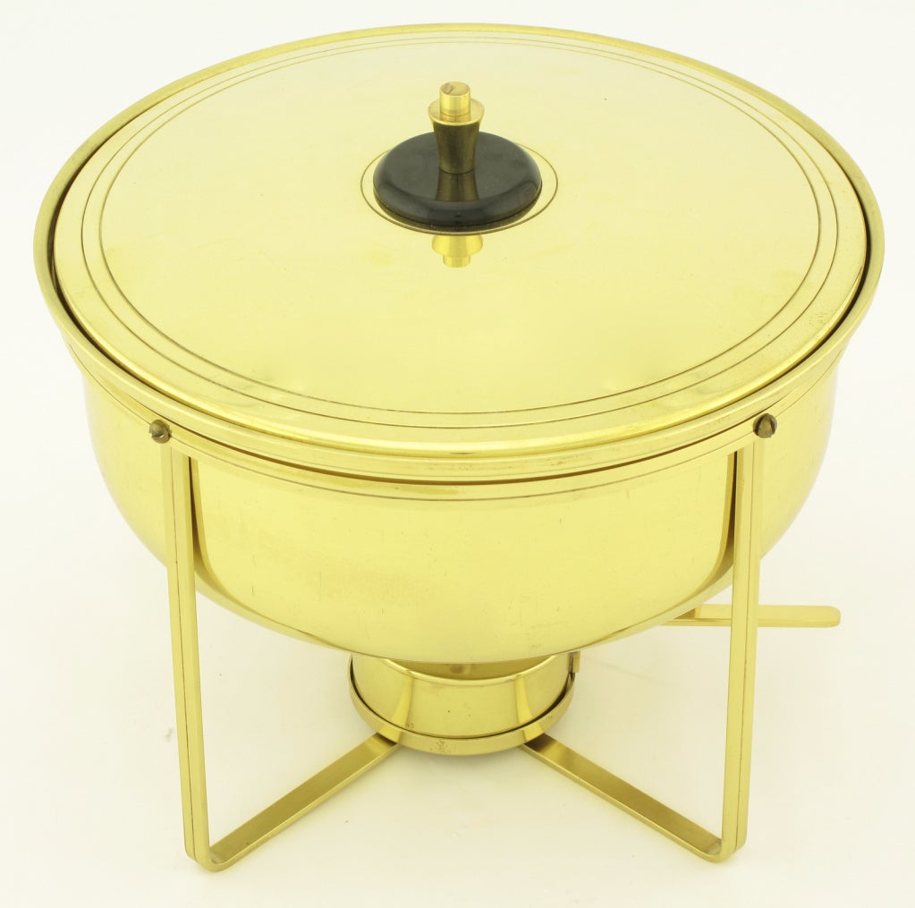 Brass coved bowl with lower warming element and stand designed by Tommi Parzinger for Dorlyn Silversmiths chafing dish with internal removable glass bowl. Sold with incised brass stand, handled warming element and top cover with brass and black