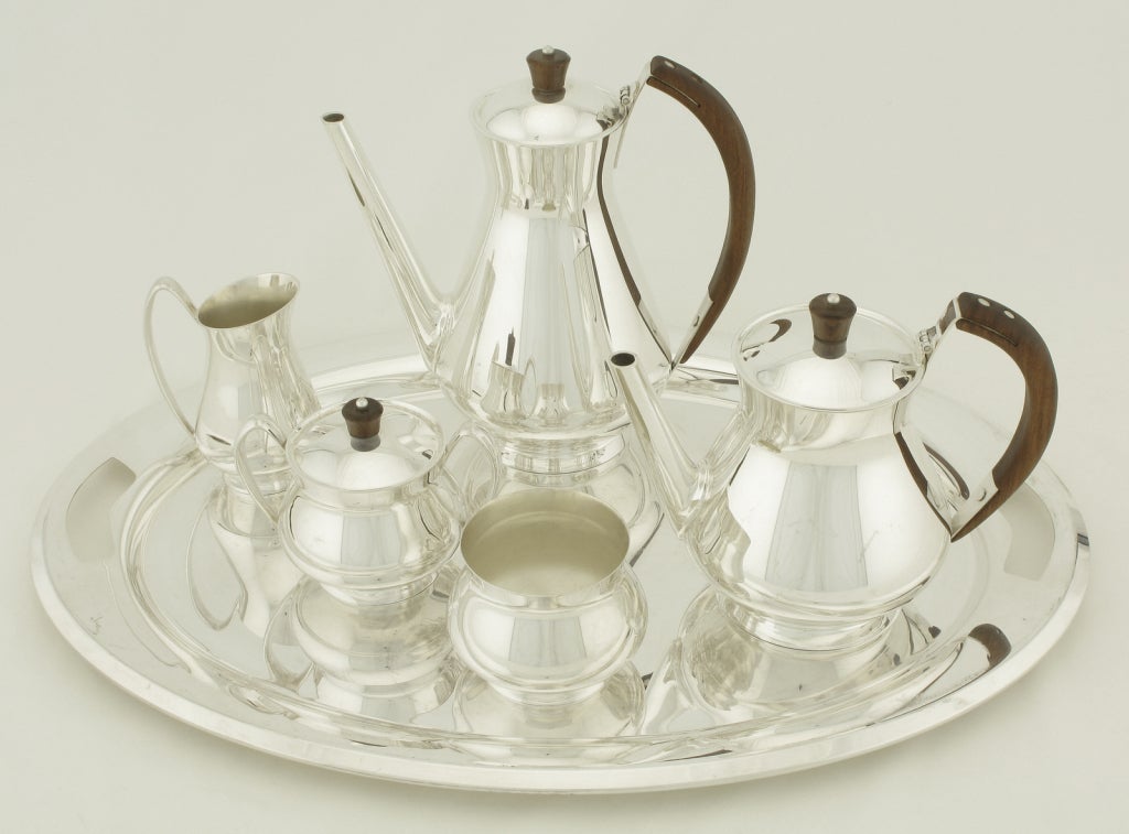 Gorham silverplate with wood six piece coffee and tea service. Set consists of coffee and tea decanters, double handle covered sugarbowl, creamer, small pot for tea bags, and tray. Possibly a Donald Colflesh design.


tray 22.5 x 16 x 1
coffee