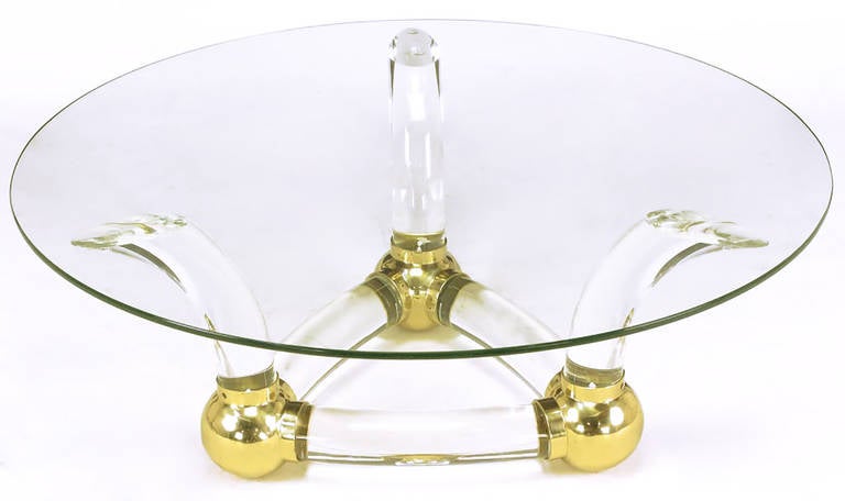 Thick curved bar Lucite and brass ball fitments coffee table. Triangular base with three horn-shaped supports. Measures: 1/2