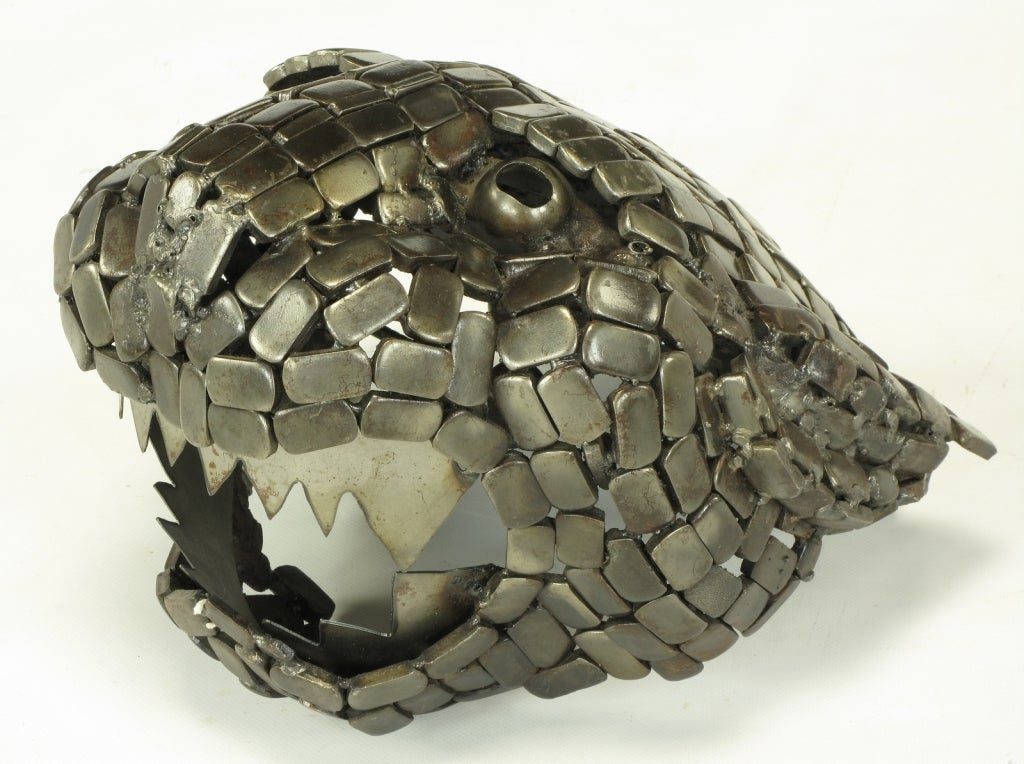 Welded metal sculpture in the shape of the head of a jaguar. Comprised of reticulated metal tiles, hollow metal ball eyes and saw tooth metal teeth.