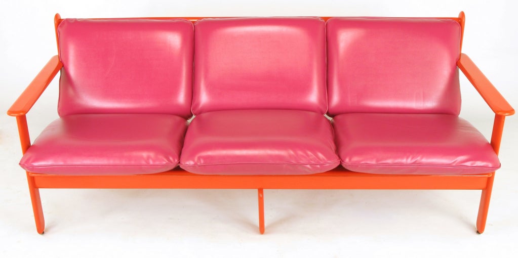 Colorful Italian three seat loose cushion sofa. Vivid persimmon orange lacquer over wood frames and magenta red-pink simulated leather seats and backs. Possibly a design offered by Stendig from the Memphis period of Italian furniture.