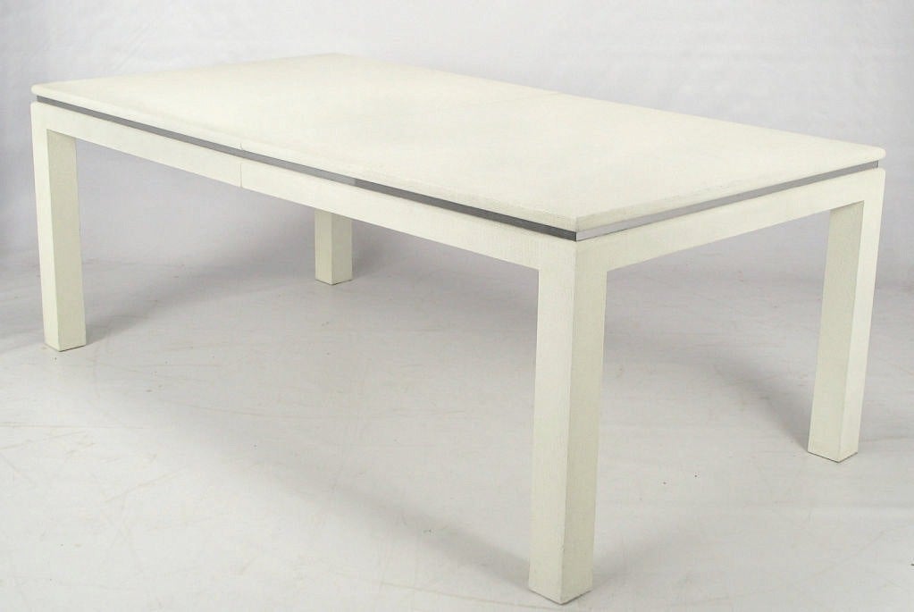 White lacquered heavy linen wrapped parsons style dining table with chrome banded accent. Heavy and well made in the manner of Karl Springer. Comes with two leaves making the overall length 108
