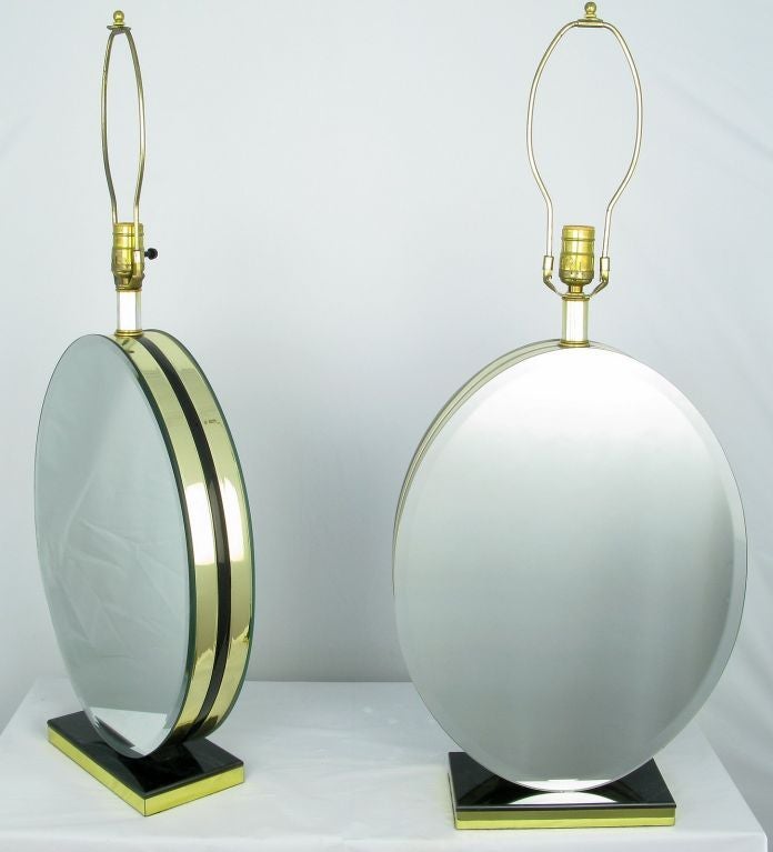 Elegant two-sided beveled mirror table lamps on a black marble and brass rectangular plinth. The mirrored bodies are comprised of black Lucite sandwiched between brass and then finished with the beveled mirror. Sold sans shades.