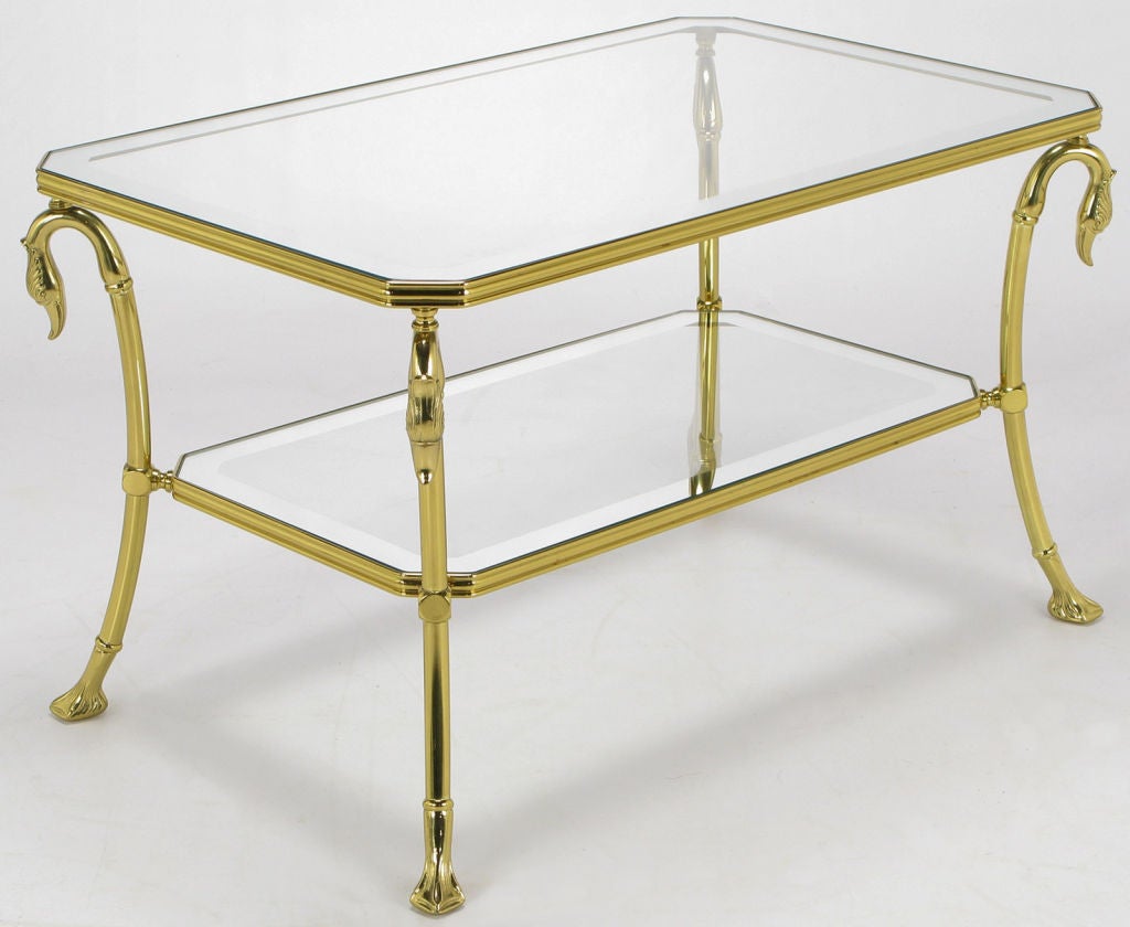 Brass two-tiered side table with four swan necks supporting the top glass tier. Lower glass tier interposed between the swan necks and the webbed feet. Canted corners and brass ribbon edged shelves. Glass surfaces bordered in mirror.