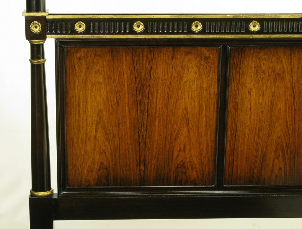 Rosewood and ebonized mahogany empire style headboard with parcel gilt detailing. Carved rosettes and top rail borders are gilt with carved fluted segments between the rosettes. Carved tassels atop the posts are gilt finished. Three rosewood panels