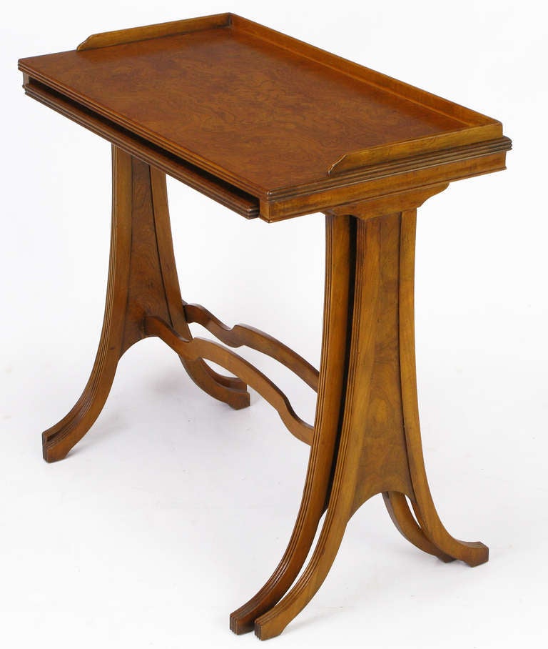 Burled walnut pair of nesting side tables by Baker Furniture, with a hint of Art Nouveau. Larger table has a distinctive top gallery. Both tables feature a ribbon carved center stretcher. Would make an excellent end table.