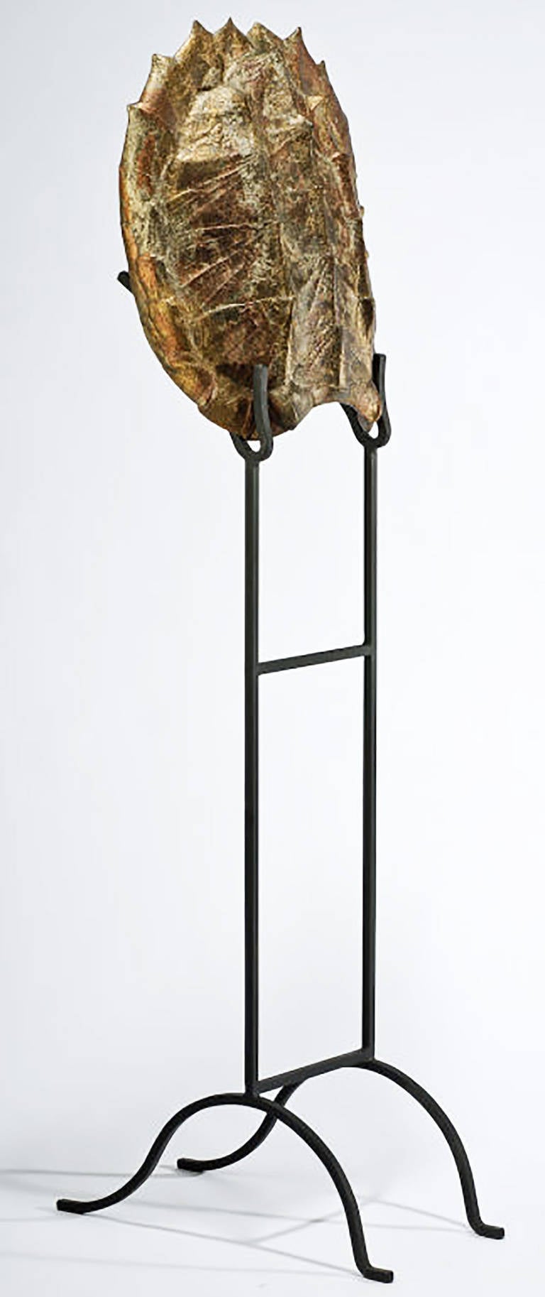 A very sculptural resin tortoise (or turtle) shell, mounted on a tall black wrought iron stand. Hand-painted finish includes accents of copper and gold coloring. Shell measures: 28