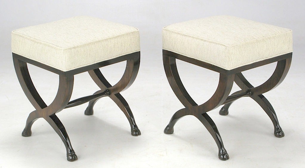 Unusual animal hoof, crossed-legged upholstered benches. From Baker's European Collection, these pieces are sometimes incorrectly attributed to T.H. Robsjohn-Gibbings. Newly covered in Stroheim & Romann natural hemp linen, with refinished wood.