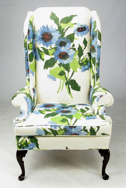 Elegantly modern pair of wingback club chairs from Hickory Chair Company. The over sized floral print linen is comprised of green, blue red and black flowers on a white ground. The front legs are cabriole carved mahogany and the mahogany back legs