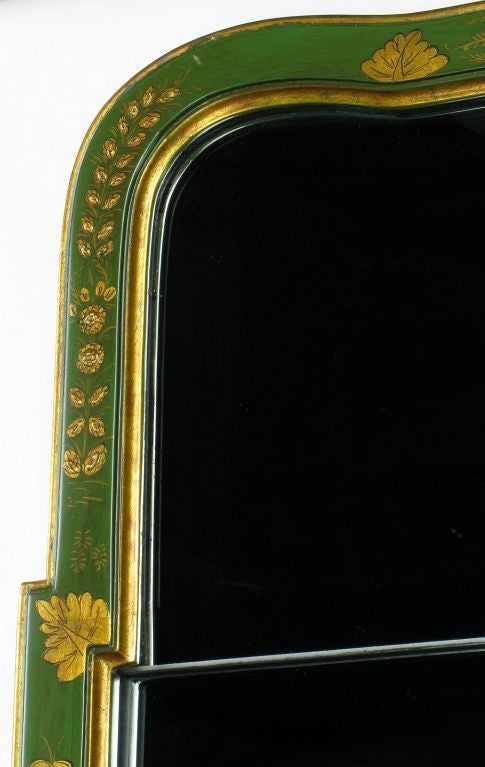 Authorized by the Colonial Williamsburg Foundation, and crafted by Friedman Brothers, fine mirror maker to the trade, this classic two-piece mirror in an emerald green lacquered wood frame with gilt Chinese characters, foliage, and borders.