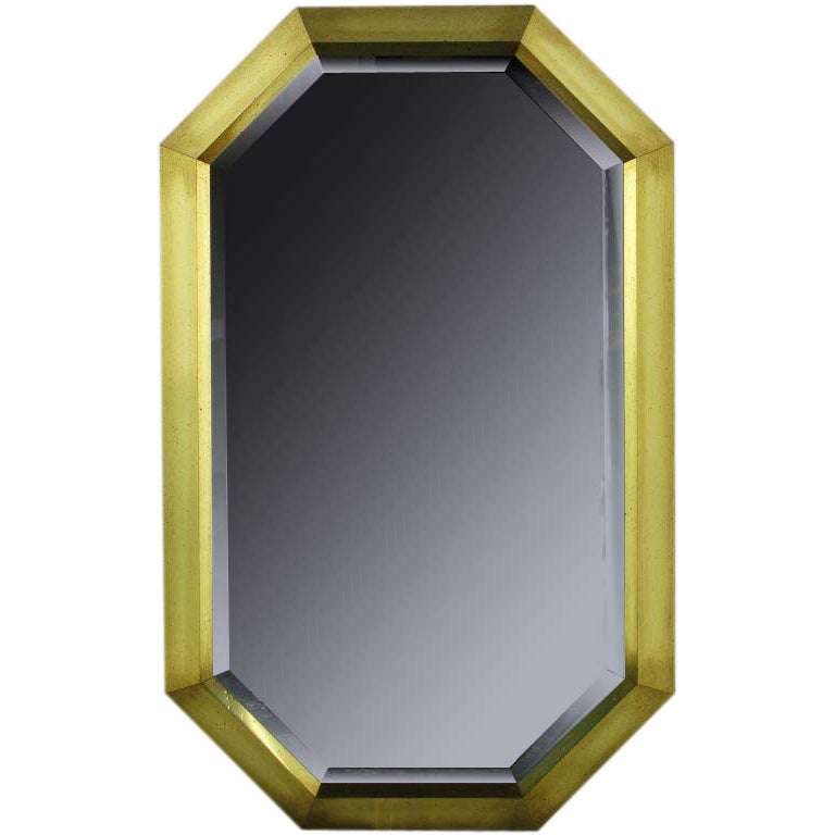 Beautiful and extremely well executed wall mirror in patinated brushed brass, clad to wood. Beveled mirror is completely backed in wood.