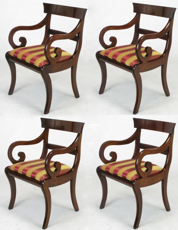 Striking set of four dining armchairs, crafted in mahogany, displaying scrolled arms and klismos style legs.  Upholstered in vintage berry red and gold stripe silk.