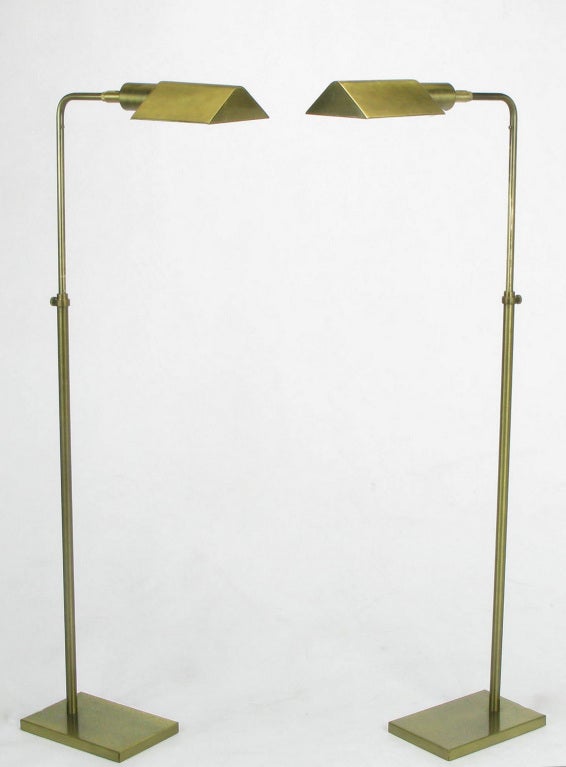 Pair of brushed antique brass adjustable floor/pharmacy lamps by Koch & Lowy. Telescopic arm adjusts eleven and one half inches up and down as well as rotates three hundred and sixty degrees. Tented socket is lacquered white on the underside and is