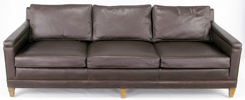 Heritage Furniture chocolate brown leather upholstered three seat Regency style sofa. Loose seat and black cushions with bleached and patinated mahogany legs. Originally sold through Colby's, Chicago finest furniture dealer for decades, until it