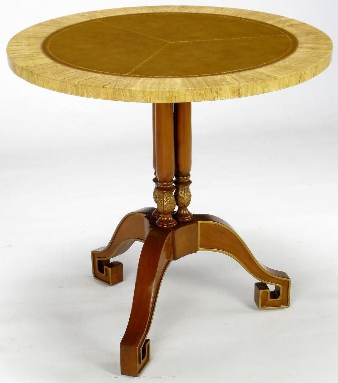 Elegant design and wonderful combination of materials on this Empire style side table. The round tooled leather top is offset by a beautiful travertine border. The parcel-gilt center three part pedestal finishes with a tripodal base with excellent