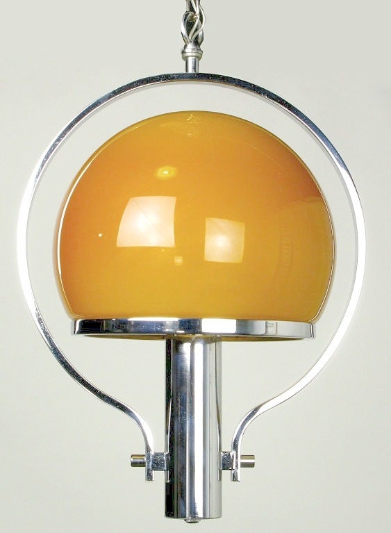 Machine age influenced modern pendant light with a beautiful amber-gold glass shade. The cased glass shade is white on the inside and amber outside giving it vibrant color when the light is on or off. Could be used as a chandelier in a smaller space.