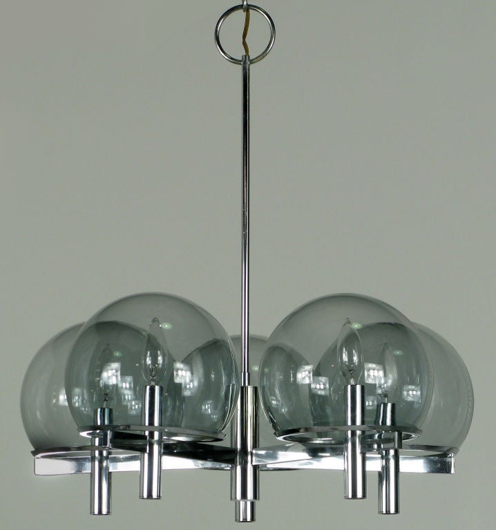 Italian modern five-arm chrome and smoked glass globe chandelier by Gaetano Sciolari. Five chrome flat bar arms connect to the center chrome column, and appear to pierce each cylinder housing the sockets. The arms also help support the chrome rims