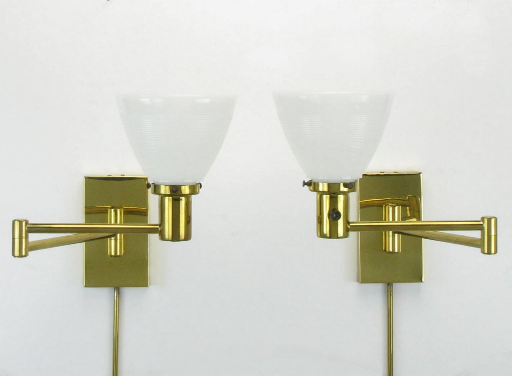 Pair of wall mounted swing arm sconces by Walter Von Nessen. Original milk glass diffusers, cord covers and linen shades. Can be either hard wired, with slight modification, or plugged into a wall outlet.
Shades are 7