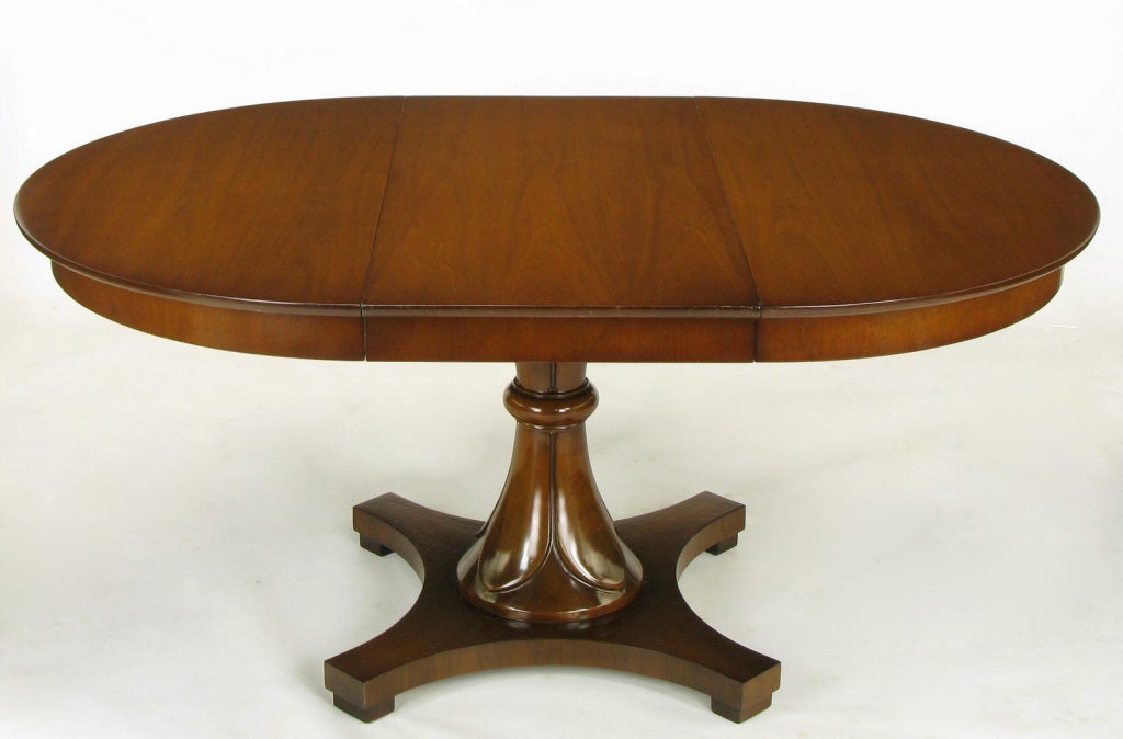 Walnut pedestal dining table with reverse trefoil base, designed by Lorin Jackson & Lee Stone for Drexel. Jackson is best known for his designs for Grosfeld House.  Hour glass shaped pedestal with center ring and flower petal carved upper and lower