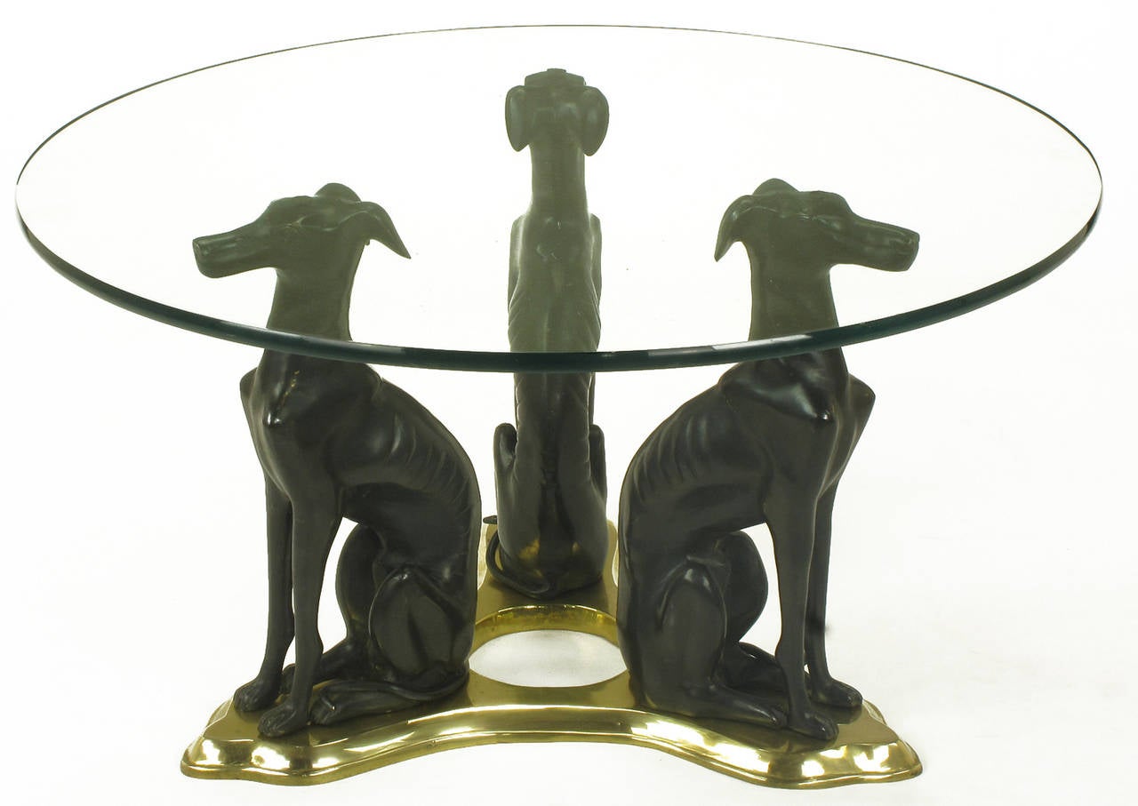 Exceptional coffee table consisting of three bronze Italian greyhounds mounted on a brass trefoil base. Round glass top is 1/2