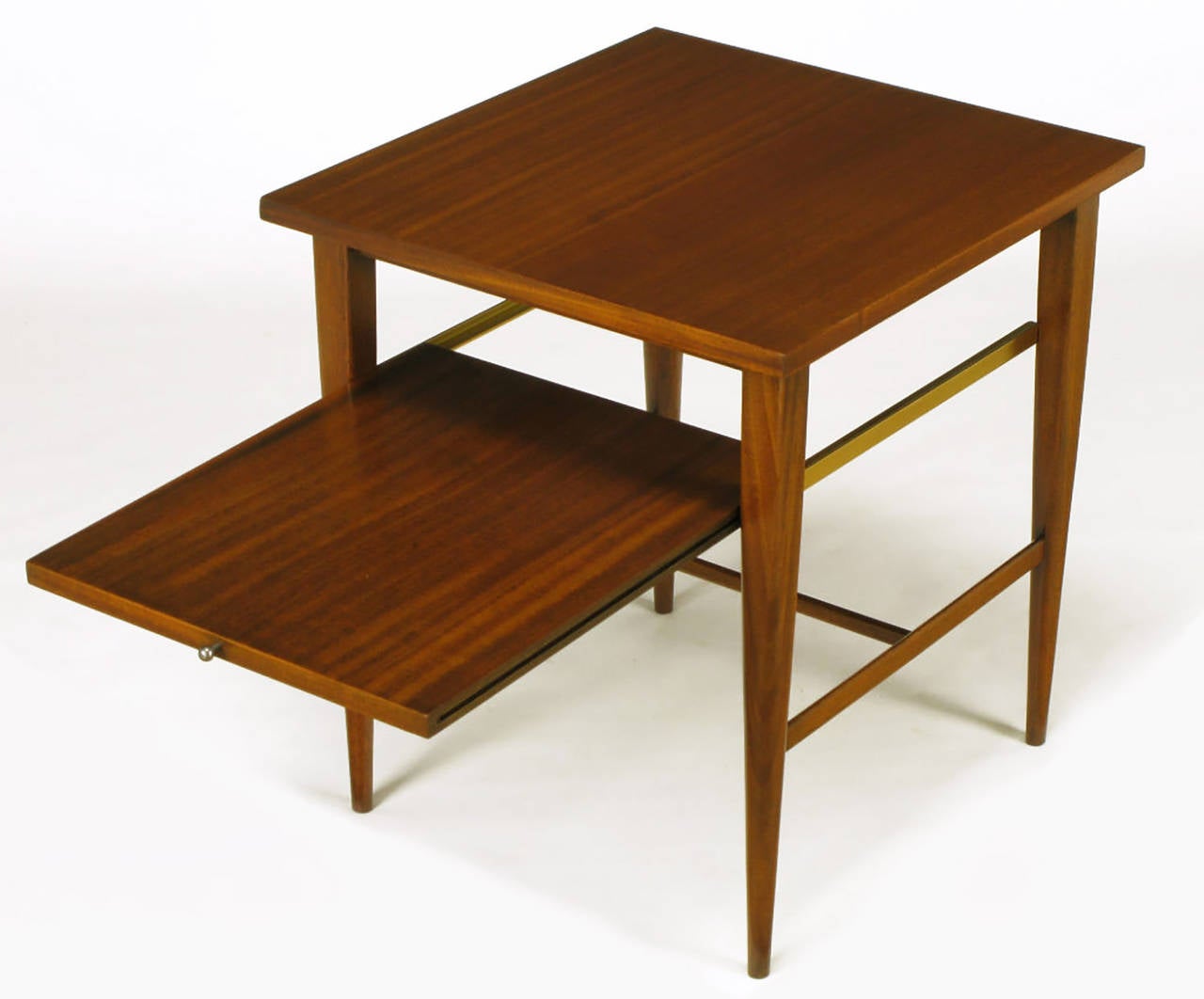 Paul McCobb for Calvin ribbon mahogany side table with H-stretchers, solid tapered mahogany legs and pull-out lower tier. Brass glides support the second tier that is accessed by a nickel ball end pull. Restored to as new condition.