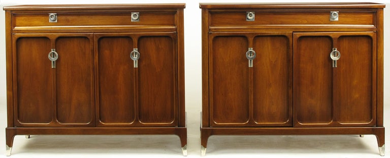 Pair of uncommon walnut and polished zinc commodes from White Furniture. Top drawer features a pair of zinc pulls with square escutcheons and four section compartment for silverware. Lower four drawers are revealed when you open the pair of double