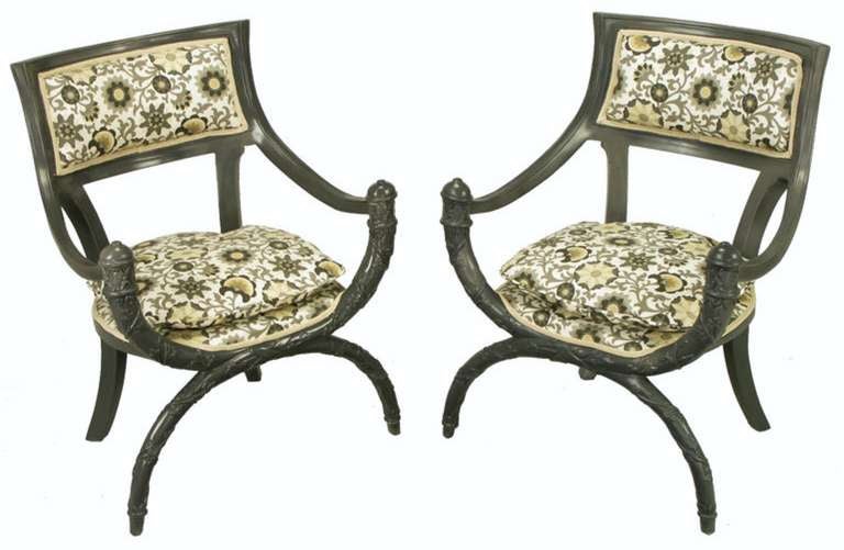 Pair of outstanding curule front arm chairs in updated slate gray lacquer over wood. Seats and backs are upholstered in a pleasant gray and saffron print on white cotton. Deep sloped arms and rear saber legs complement the rounded seat and carved