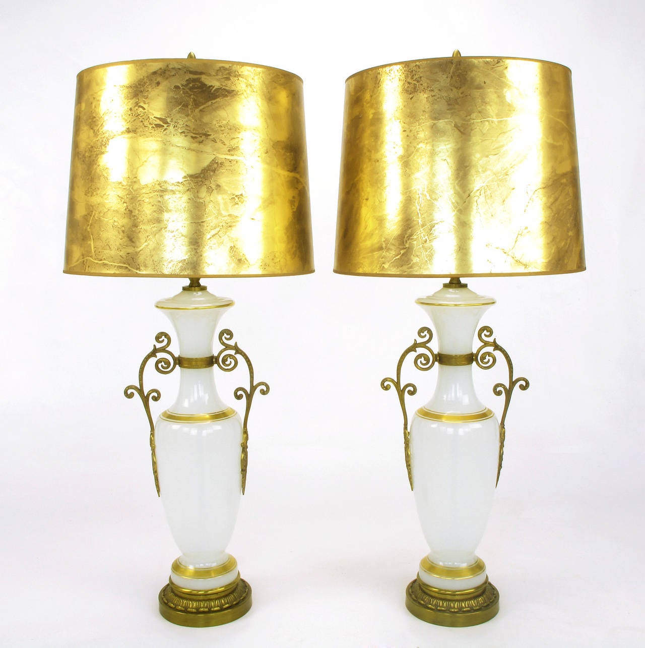 Pair of Chapman neoclassical white milk glass vase shaped table lamps with gilt striping. Filigreed brass handles and cast brass base, brass stem and double socket cluster. Sold sans shades.