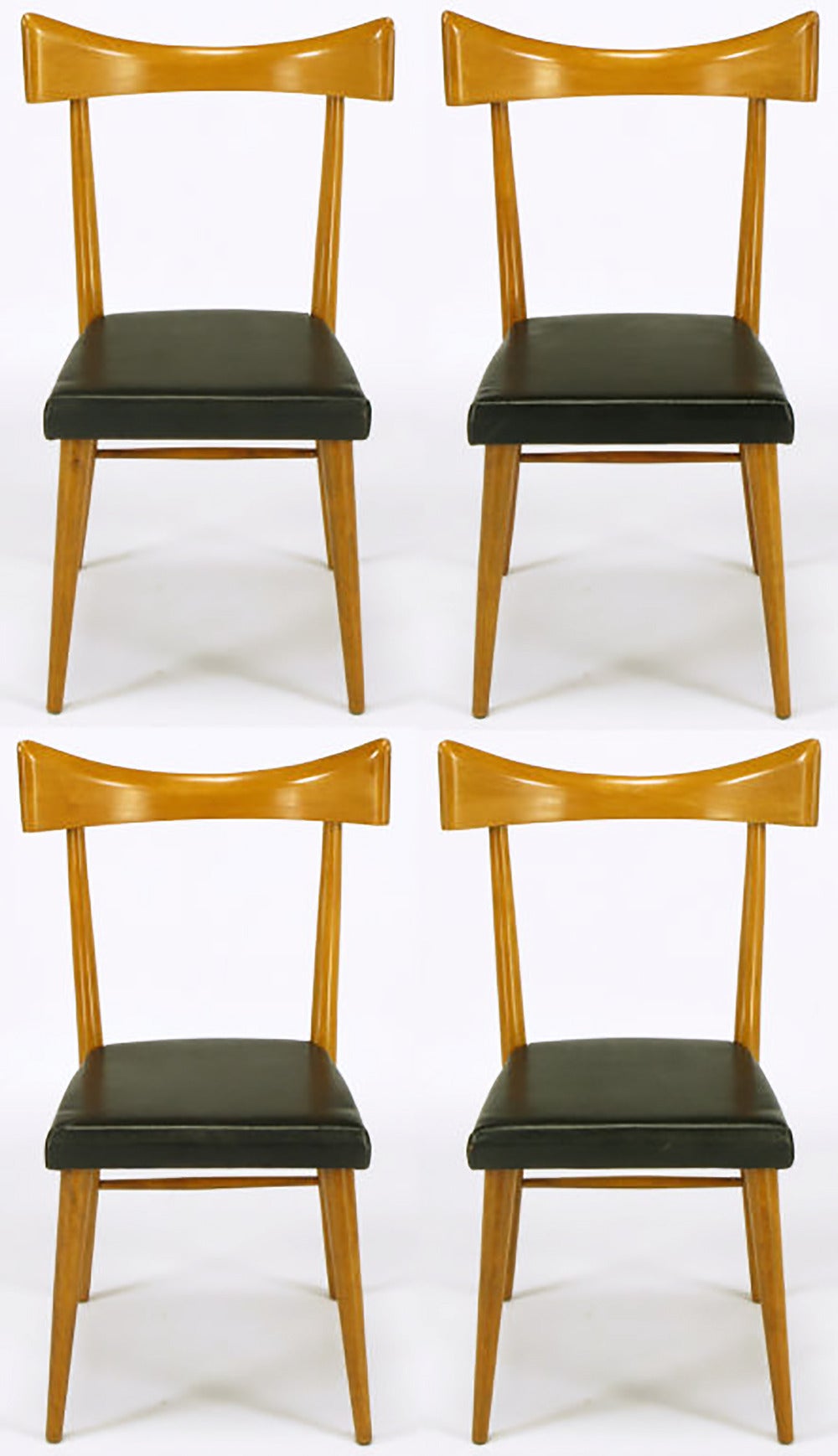 Rarely offered set of four Paul McCobb for Winchendon maple dining chairs with open back and large curved top rail. Free of ornamentation, the clean lined shape is only broken up by the black vinyl seat covering. Large curved M-shaped top rail is