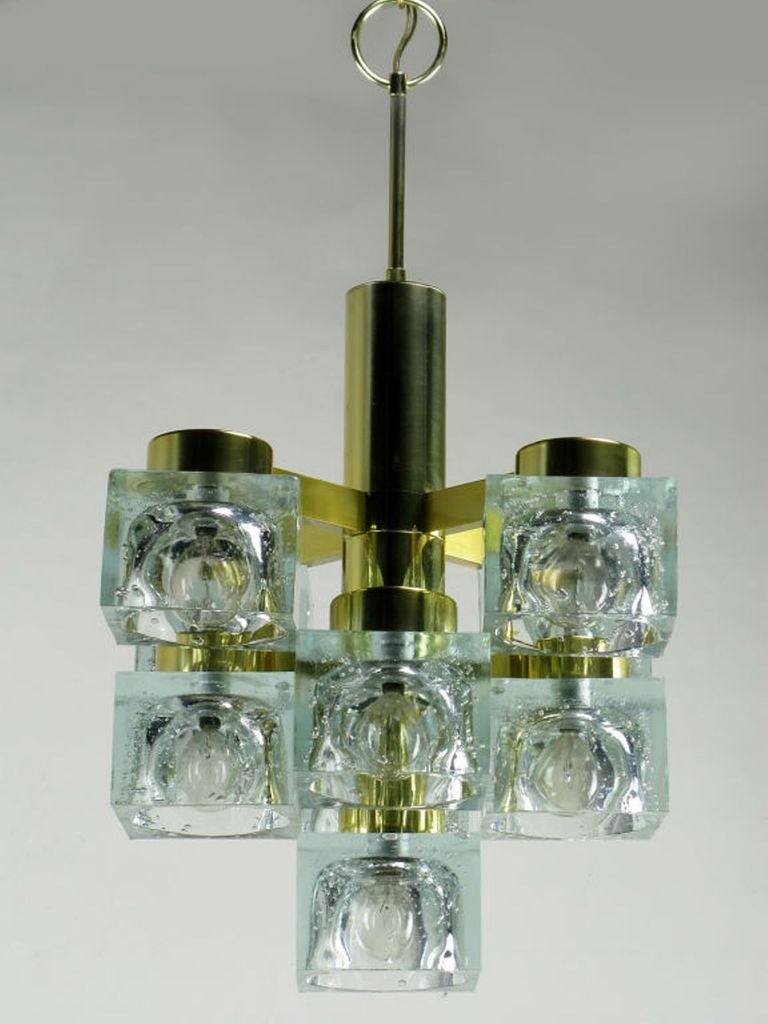  A Lightolier chandelier by Italian lighting designer Gaetano Sciolari, featuring nine square clear crystal shades. The frame is a brass tube with nine lights on three tiers, in the form of an inverted pyramid.