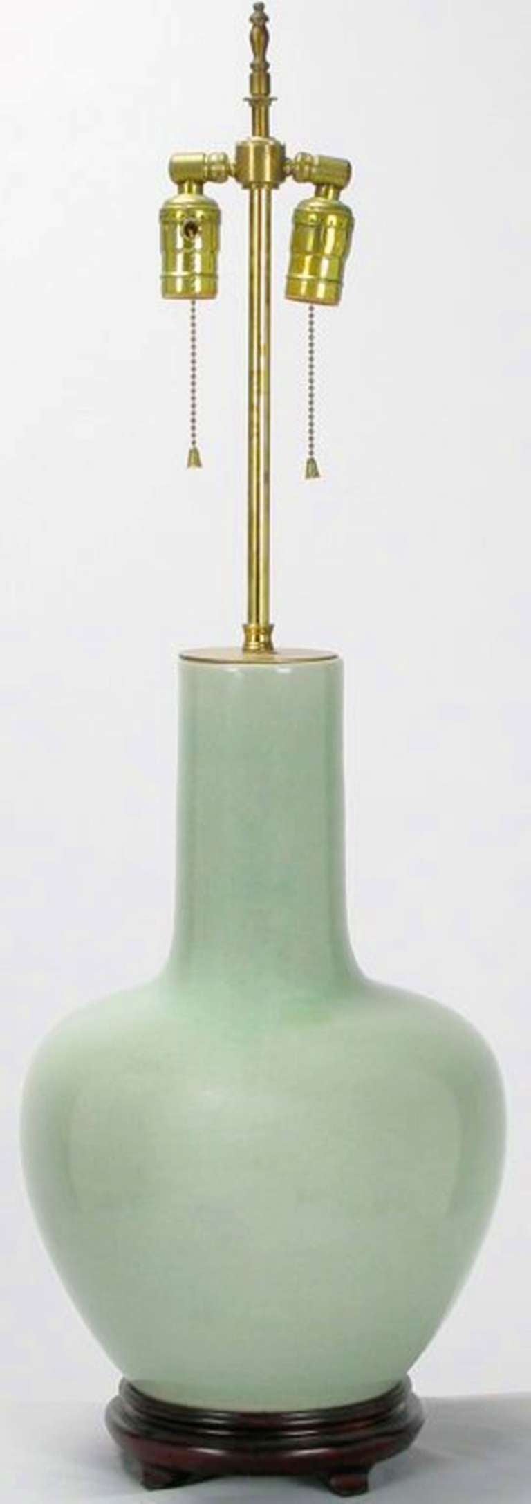 Celadon-green glazed ceramic gourd form body. Carved wood base and brass cap. Adjustable stem and dual socket illumination with on/off pull chains. Slight crackle to glazed finish. Sold sans shade.