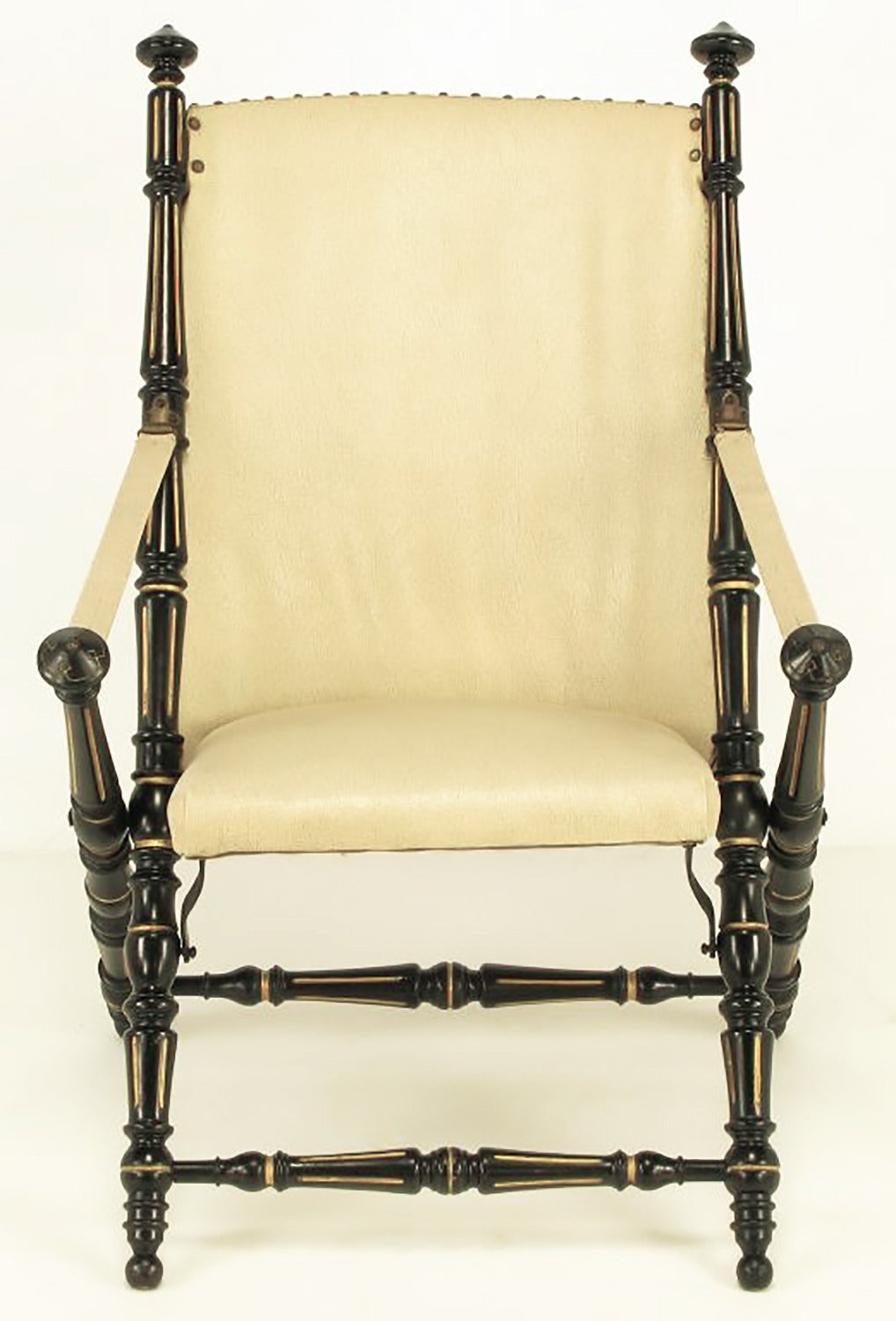 Heavily carved wood English style Campaign chair finished in black lacquer and parcel-gilt detailing. Ivory vinyl upholstered seat and back with brass nailheads. Plywood backed seat with metal supports.