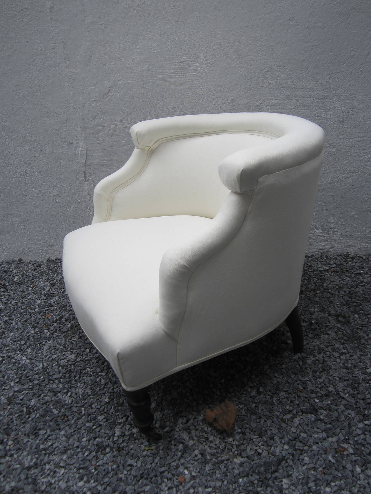 19th century barrel chair newly upholstered in white linen....black painted leg and four casters.