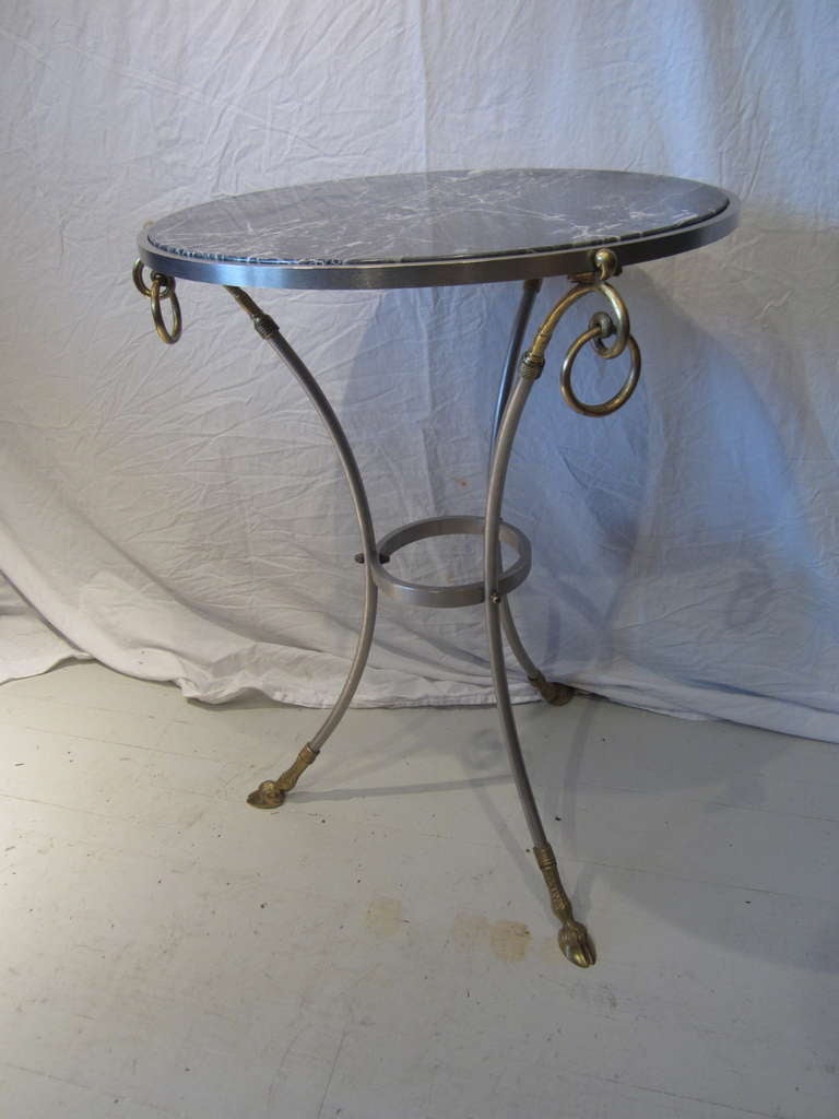 Elegant marble-top table with a steel and brass base in the French Regency style.