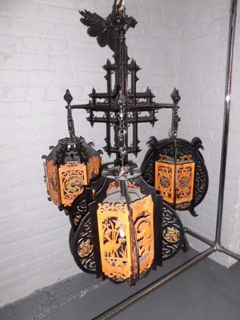 A very unusual Asian style chandelier with a central painted brass shaft and three expertly sawn [ fretwork ] painted wood lanterns. Each lantern different from the other with motifs ranging from Asian characters to animals such as cranes and