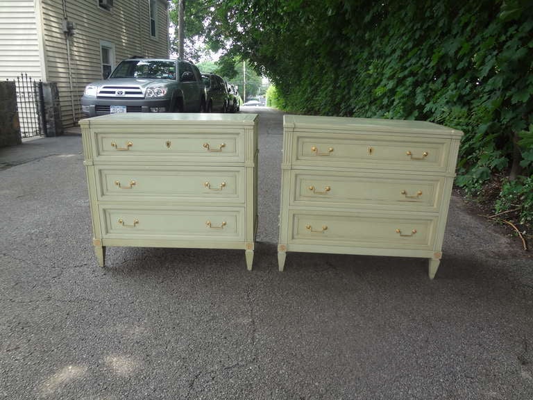 A pair of original paint neoclassical revival 3 drawer commodes with gilt brass hardware and rosettes . They are labeled 