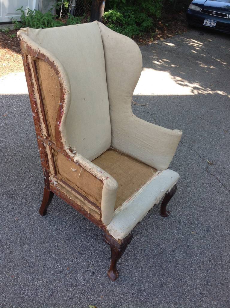 A period English George I walnut wing back armchair circa 1720. The two back legs were replaced in the late 19th or early 20th century. Very nicely carved. Has been stripped and needs refurbishing and upholstery.