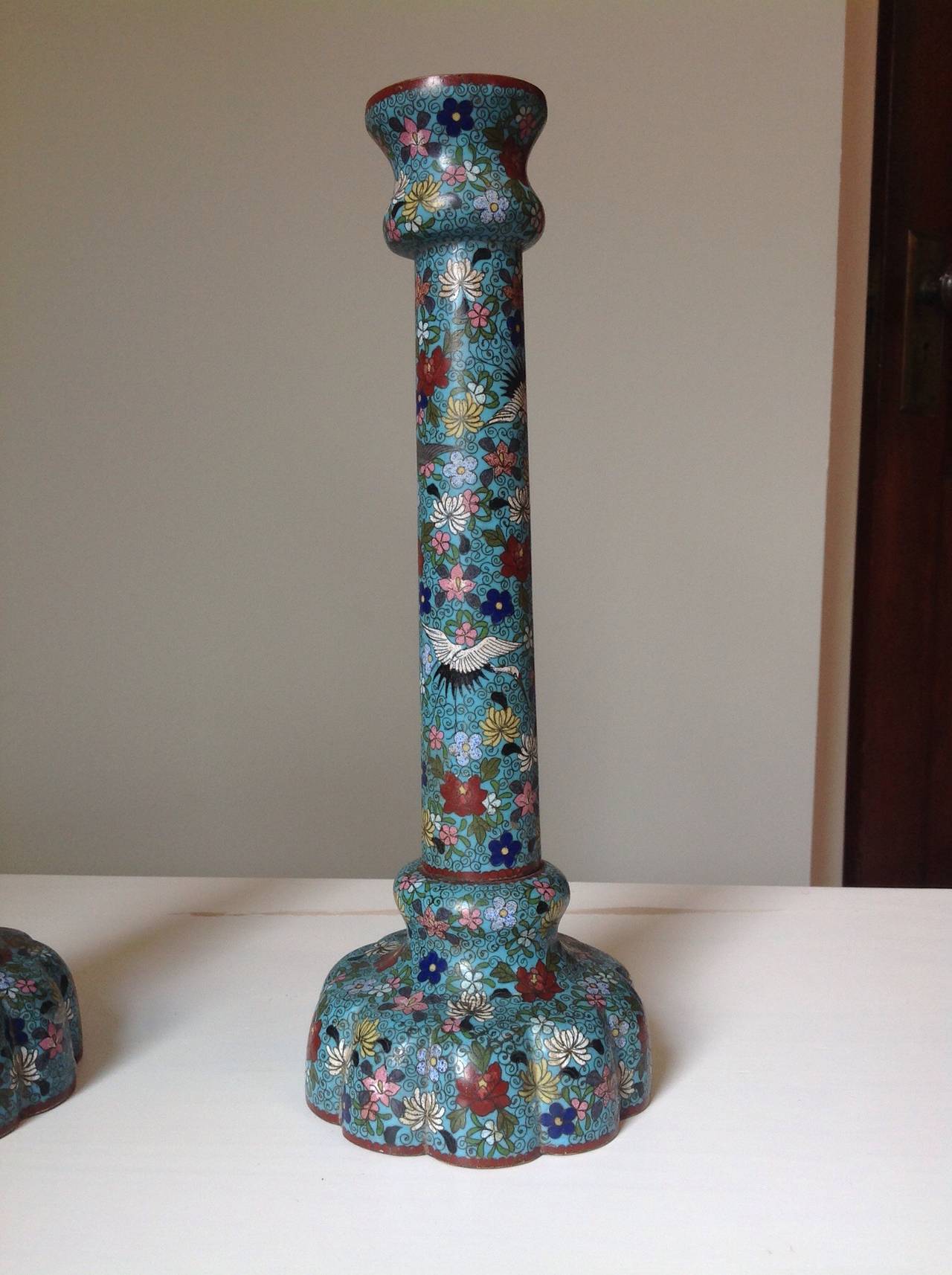 An unusual and very decorative pair of late 19th, early 20th century Chinese cloisonné́ enamel candlesticks with aqua blue background and intricate flower (chrysanthemums, roses, lotus etc...) and crane motif. The cloisonné́ work is beautifully