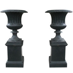 Pair of petite cast iron urns on pedestals marked Fiske