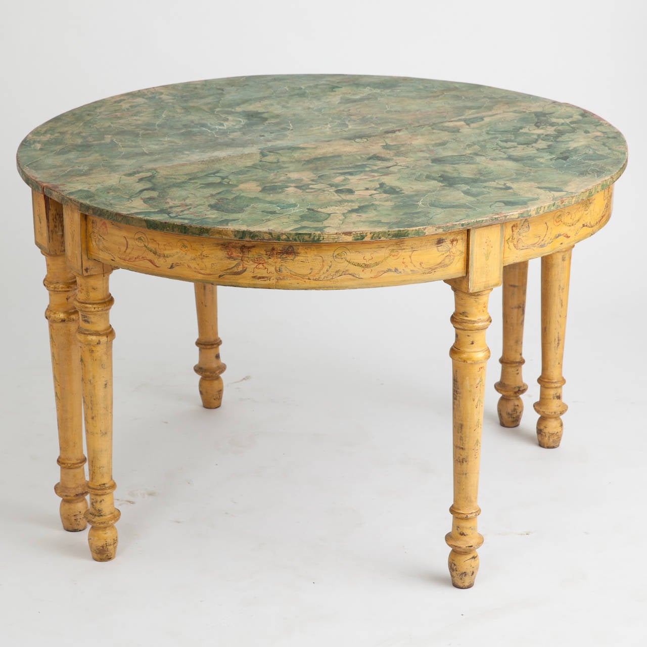 A pair of outstanding Italian demilune tables with an original painted base in a sunny yellow with a green faux marble top. The base has traces of the original painted drawings of whimsical mermaids with long feathery tails interspersed with a