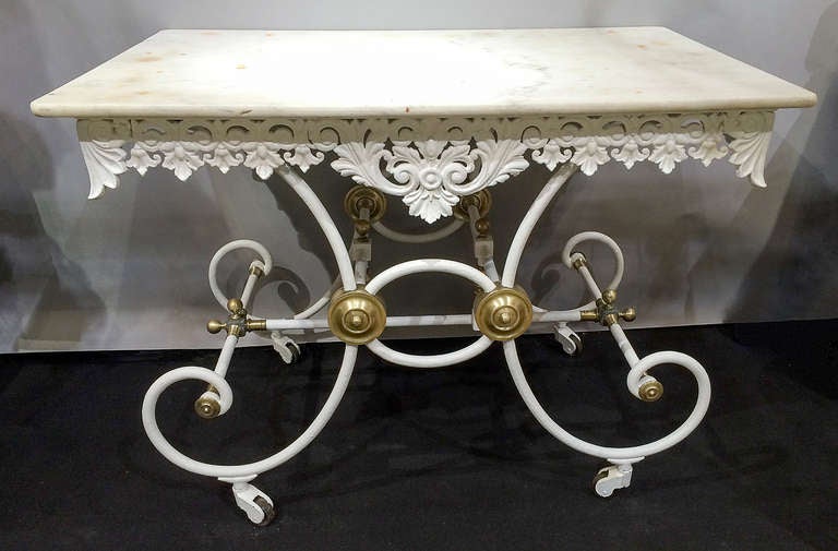 A great example of a French cast iron bakers table with original marble top. The elaborate apron is in excellent condition on all sides and the brass details on the body and legs are perfect. The table retains its original wheels which is unusual as