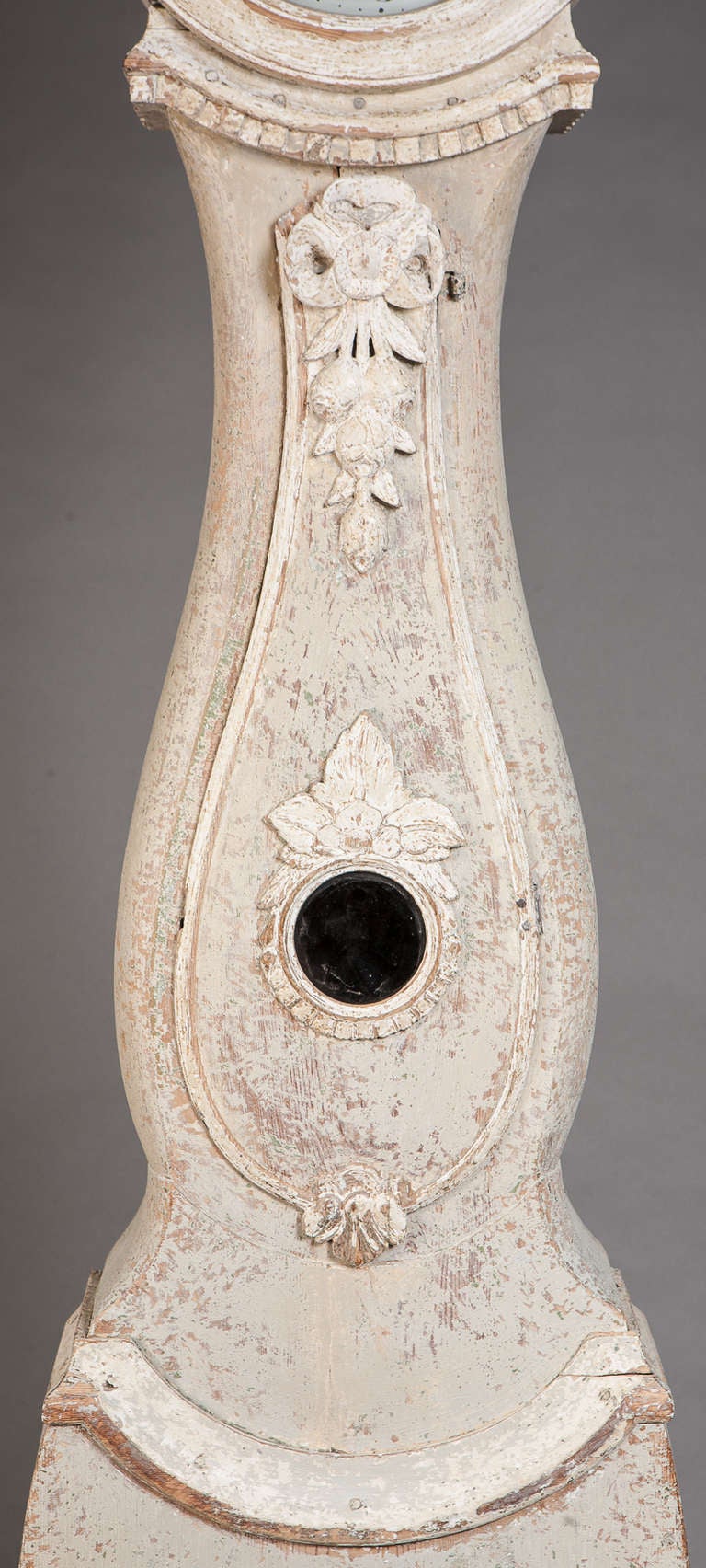 A Swedish bridal clock from Jämtland, with elaborate carved floral decoration and carved crown on the bonnet. Dry scraped to original paint surface of pale cream contrasted with white on the carvings. Traces of original gilt remain.