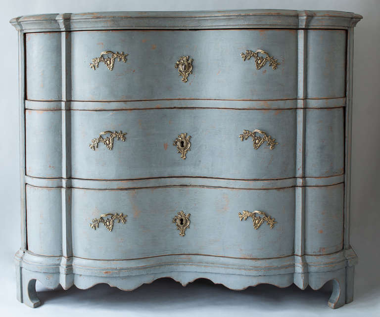 A fine Swedish, Baroque period chest of drawers in carved oak with an old blue paint surface. The details of this piece are excellent with curved insets on both sides and gently curved drawers with original brass hardware lock and key. This is a